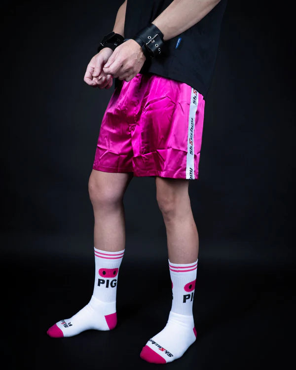 Person wearing pink shorts and white socks with pink accents on a black background