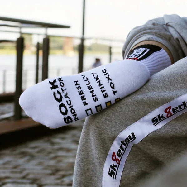 White socks with text and a brand logo on a person's foot outdoors.